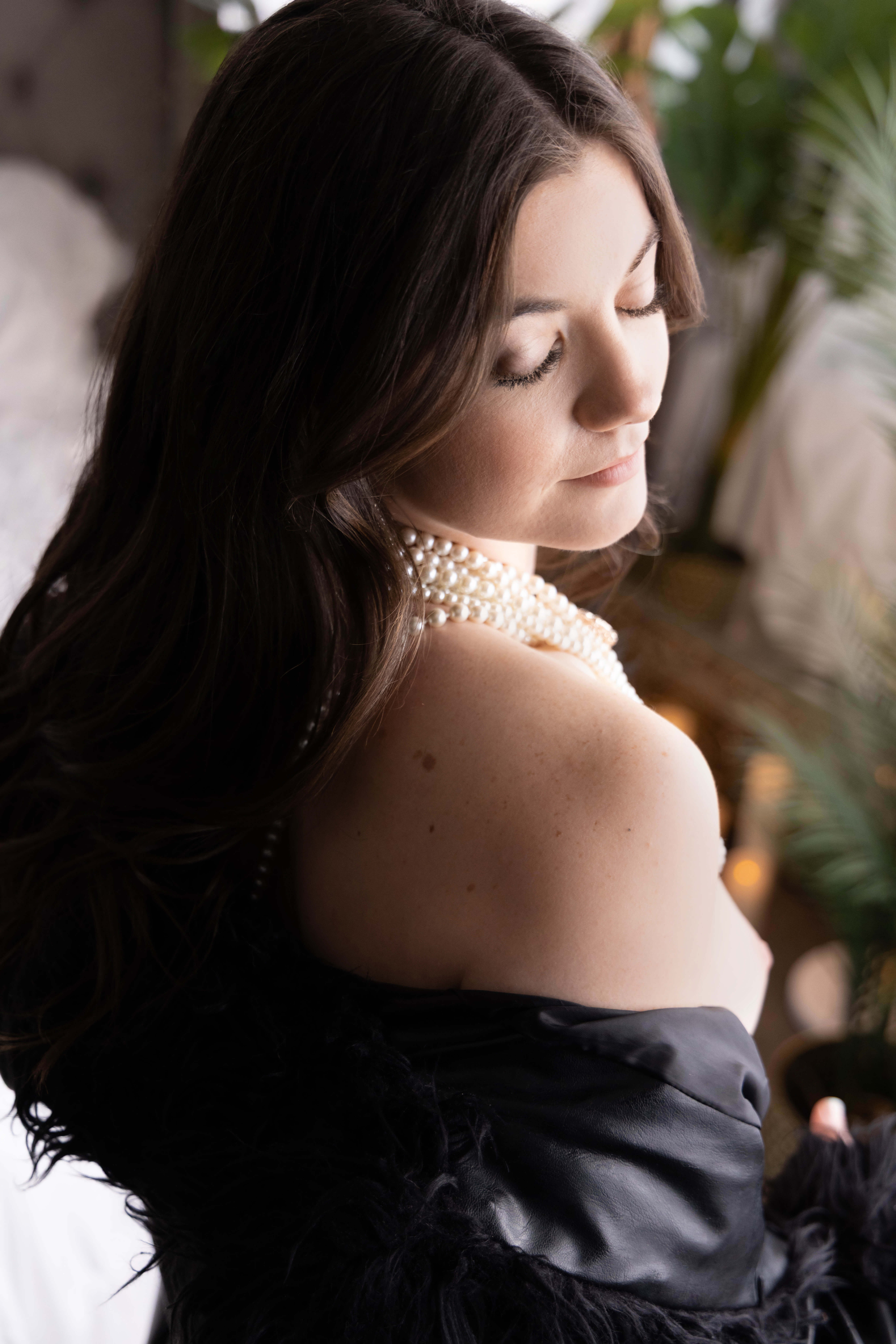 Woman looking over her shoulder in a black off-the-shoulder top during a boudoir session.